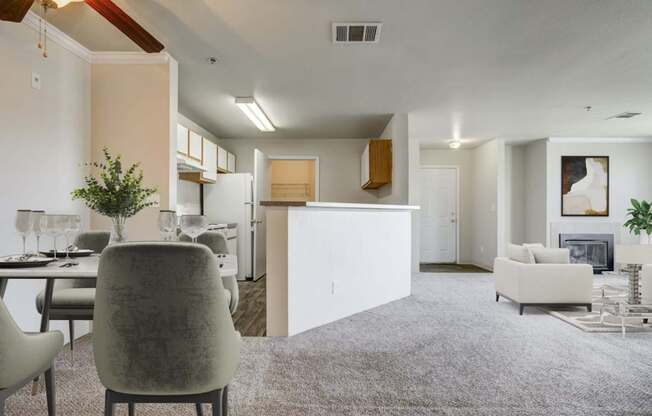 A modern living room with a grey carpet and a dining table set for two.