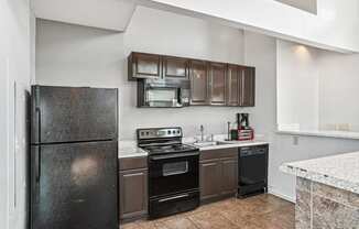 Kitchen with black appliances and brown cabinets at Wellington Farms, Charlotte