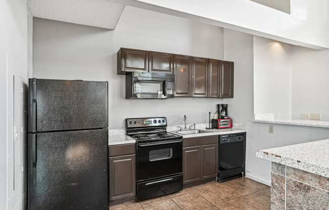 Kitchen with black appliances and brown cabinets at Wellington Farms, Charlotte