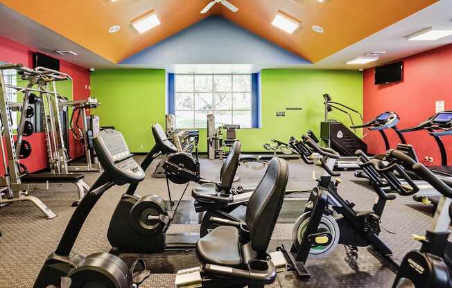 A gym with a variety of exercise equipment including treadmills, stationary bikes, and weight machines.