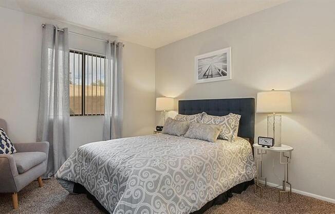 One-Bedroom Apartments in Mesa, AZ - Mesa Station - Cozy Bedroom with Carpeted Flooring, Wall Art, Queen Bed, and Large Window