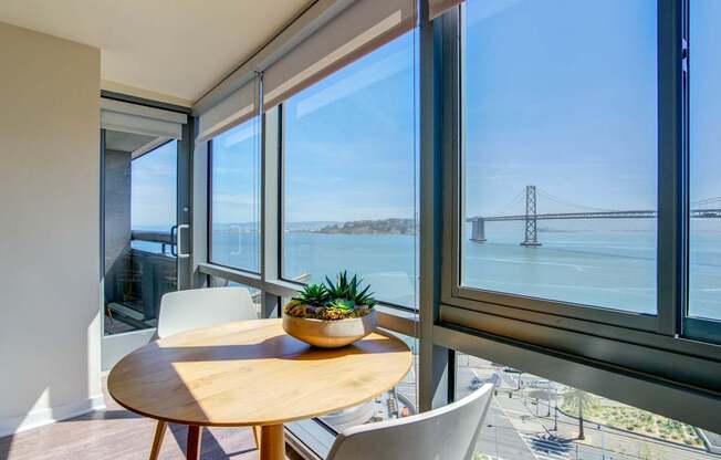 A table with a pineapple on it sits in front of a window with a view of a bridge.