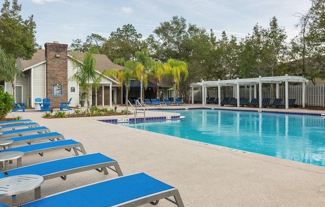 a large swimming pool with blue lounge chairs