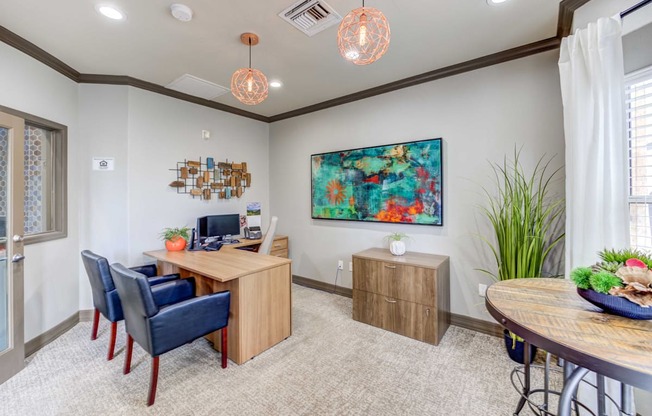 A room with a wooden desk and blue chairs.