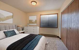 a bedroom with a bed and a dresser and a window. Fargo, ND Prairiewood Meadows Apartments