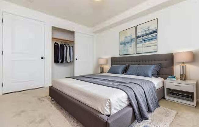 A bedroom with a bed, nightstand, and a painting on the wall.