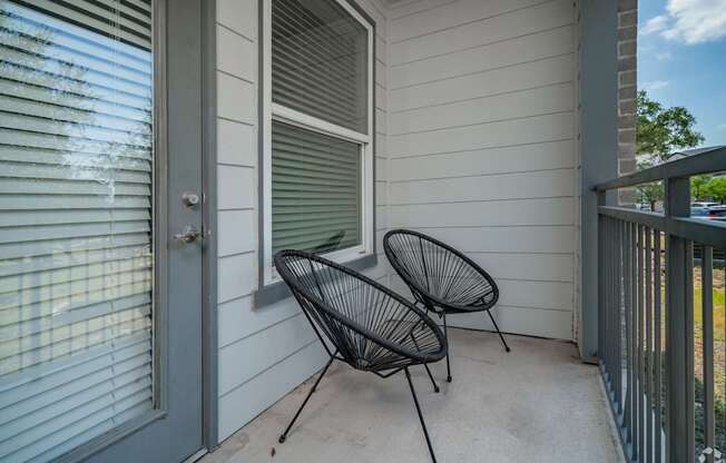 Two black chairs are on a porch.