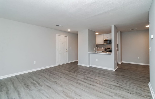 the living room and kitchen of an apartment with wood flooring