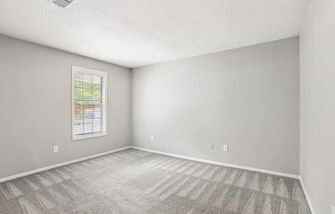 A room with a window and carpeted floor.