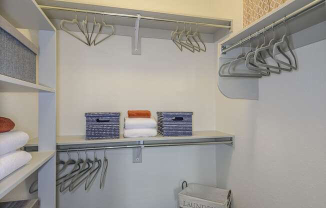 a walk in closet with folded towels and a rack of hangers