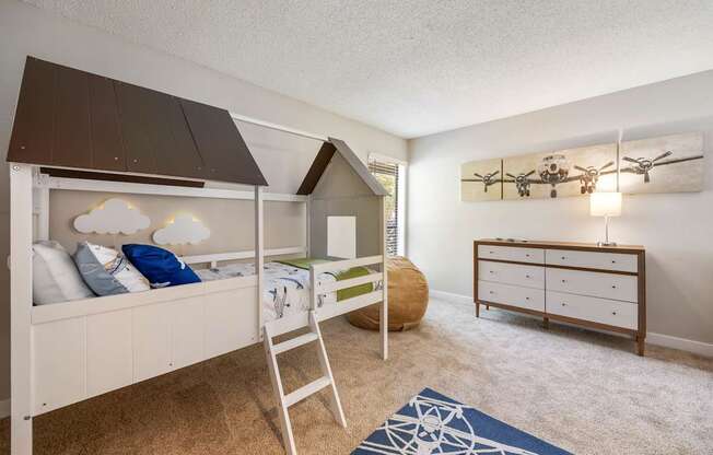 A room with a bunk bed and a dresser.