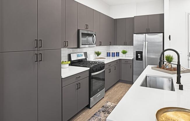 a modern kitchen with stainless steel appliances and white counter tops at Aura Vegas Apartments, Las Vegas, NV 89103