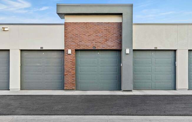A building with a brick chimney and grey garage doors.