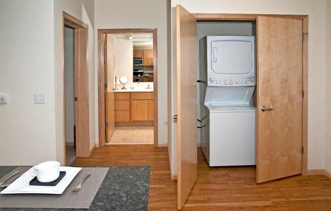 A kitchen with a refrigerator and a dining table with a plate and cutlery on it.
