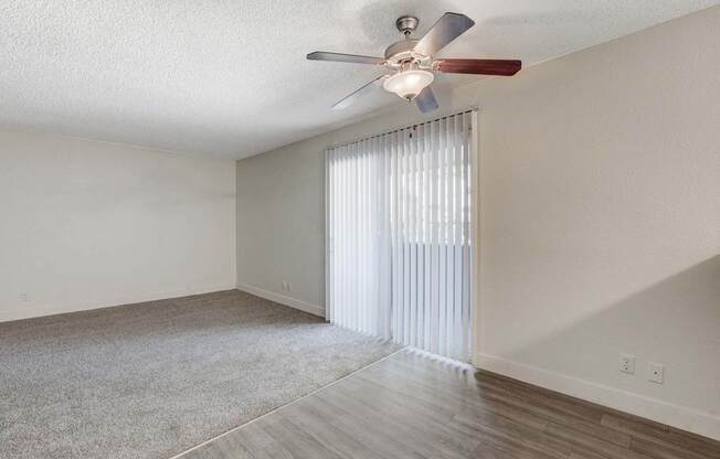 A room with a ceiling fan and a window with blinds.