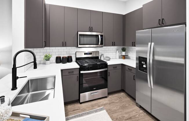 a kitchen with stainless steel appliances and gray cabinets at Aura Vegas Apartments, Las Vegas, 89103
