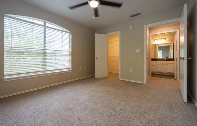 Alternate view of guest bedroom looking into walk in closet and bathroom across the hall. On second floor with carpet, ceiling fan, and well lit window