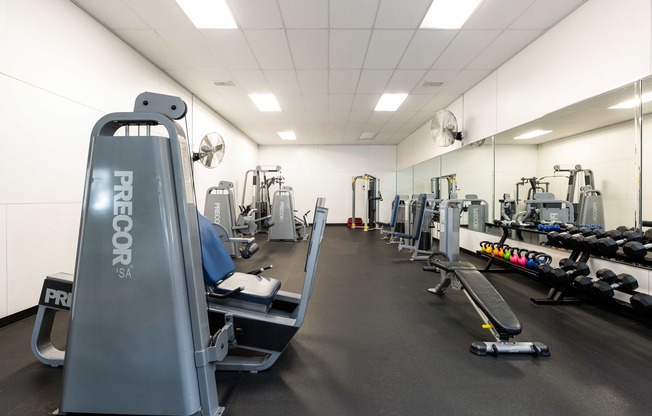 a gym with cardio equipment and weights on the floor