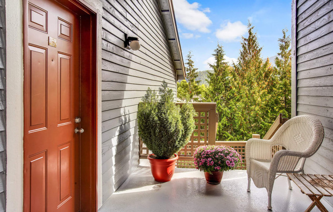 front porch with chairs and plants and a door