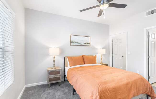 a bedroom with an orange bed and a ceiling fan