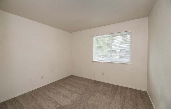A room with a carpeted floor and a window with blinds at Pepperwood Apartments, California, 95661