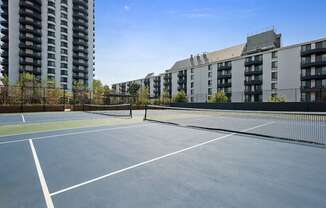 A tennis court surrounded by buildings.