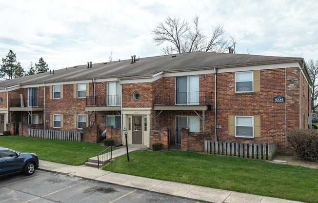 A brick apartment building with a car parked in front.