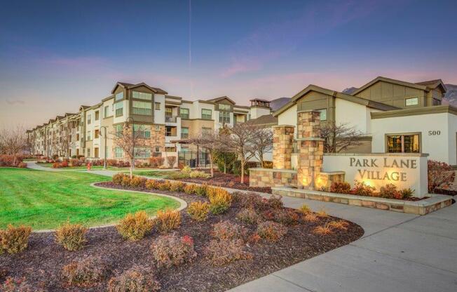 Park Lane Village apartments lit up at dusk- green and white exterior buildings