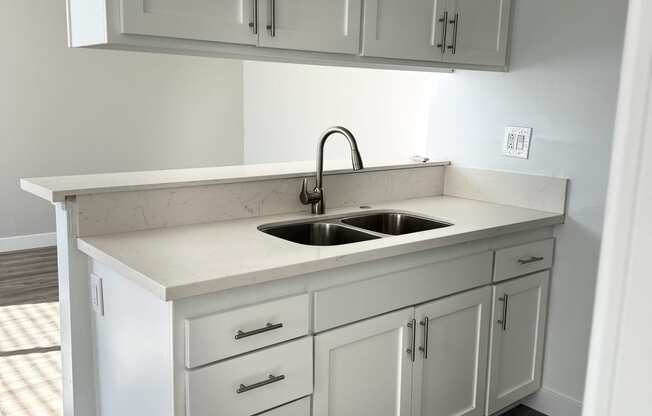 an empty kitchen with white cabinets and a sink