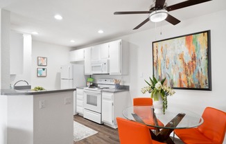 a white kitchen and dining room with orange chairs and a table