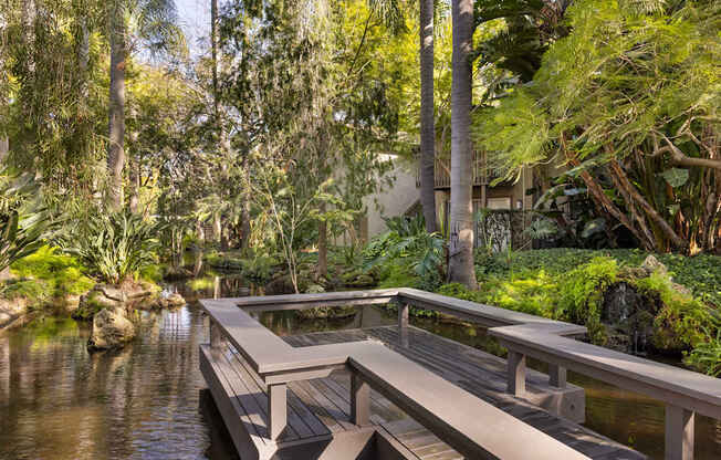 A wooden walkway over a body of water surrounded by greenery.