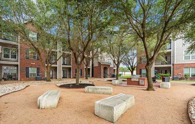 A courtyard with a sandy ground and a few trees.