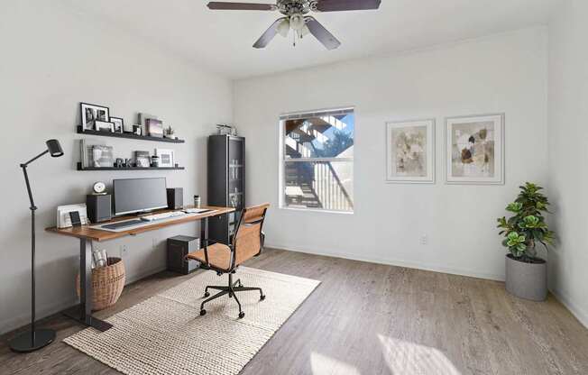 Affordable Apartments in Austin, TX for Rent- Huntington Meadows-  A room with a desk, chair, and a ceiling fan.