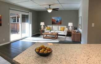 A bowl of oranges sits on a counter in a well-lit room.