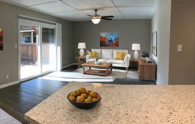 A bowl of oranges sits on a counter in a well-lit room.