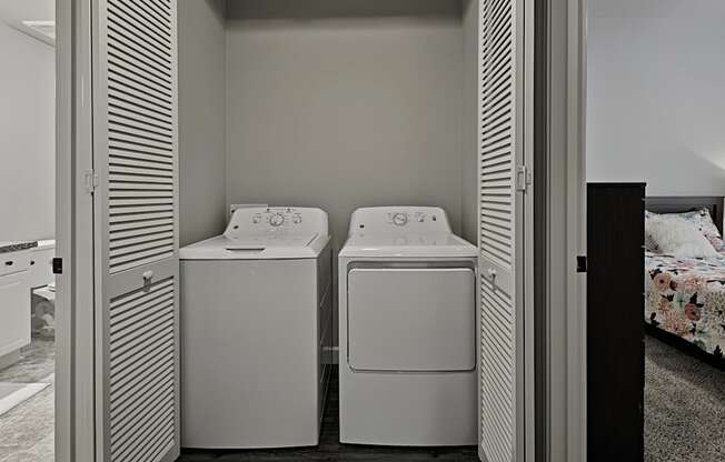 a laundry room with two washers and a dryer next to a bed