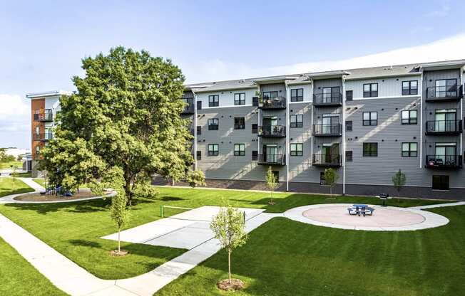 an exterior view of Golden Aspen Flats with a pickle ball court, picnic area, grass and trees