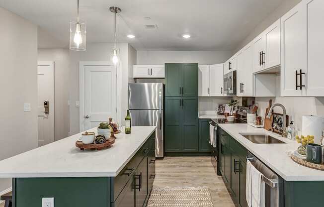 a kitchen with green cabinets and white counters and a stainless steel refrigerator at Edgebrook Residences, Merrimack, NH 03054