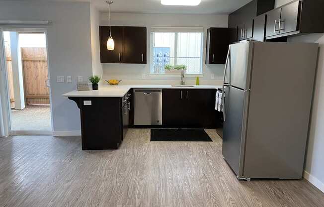 A kitchen with black cabinets and a wooden floor.