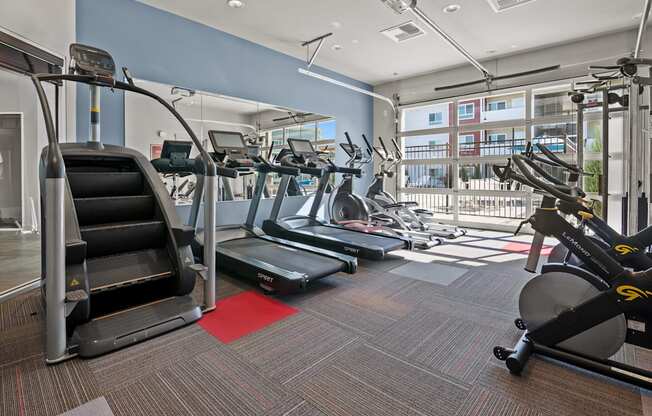 a gym with treadmills and other exercise equipment in a building with a balcony