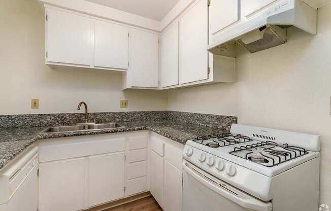 a kitchen with white appliances and granite counter tops and white cabinets