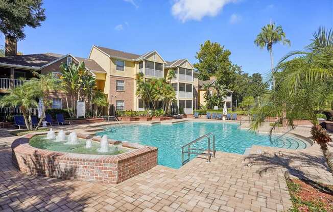 A pool with a fountain in the middle of a brick patio.