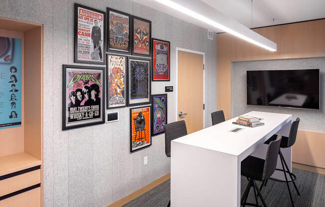 a room with a table and chairs and a wall of framed movie posters