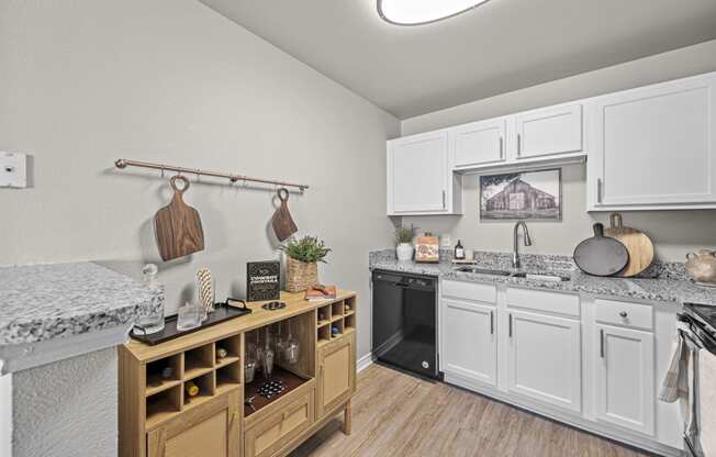 a kitchen with white cabinets and granite counter tops and a black oven and a sink