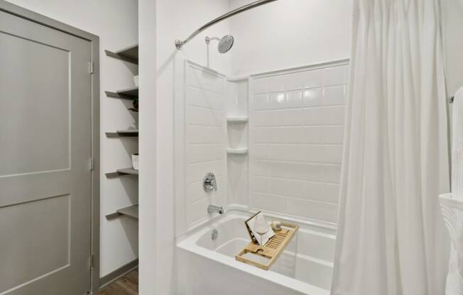 a bathroom with a shower and a tub and a closet at The Depot in The Depot Raymore, MO 64083