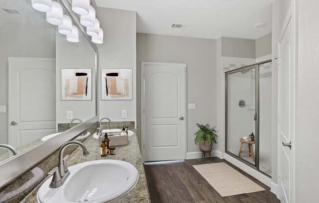 A bathroom with a sink, mirror, and wooden floor.