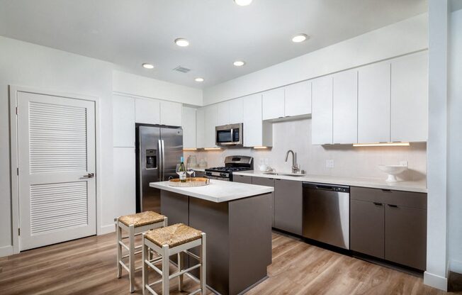A kitchen with a refrigerator, microwave, and a sink.