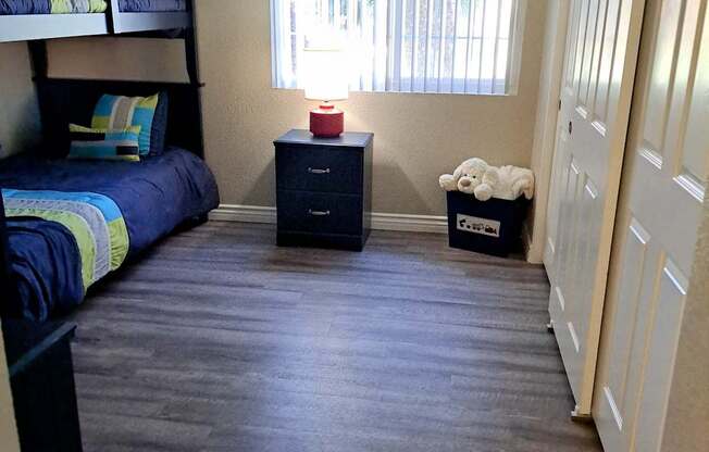 A room with a bunk bed, a nightstand, and a dresser.