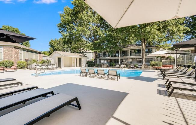 Tanning chairs and umbrellas in poolside lounge area at The Arbor in Blue Springs, Missouri 