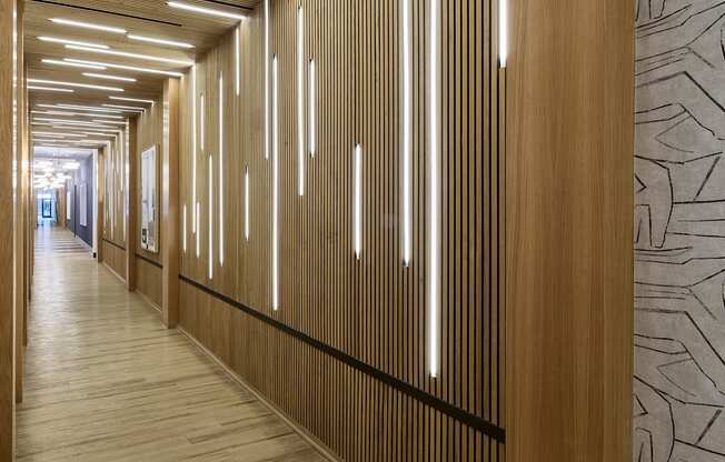 A long hallway with wood paneling and lighting on the ceiling.